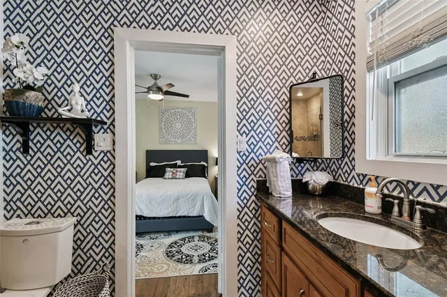 a en suite bathroom with a granite countertop sink and a mirror