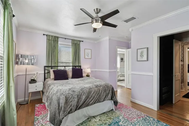 a bedroom with a bed and a large window with wooden floor
