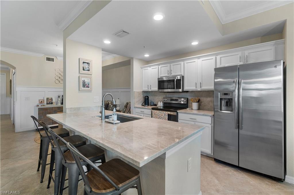 9834 Giaveno Circle, Unit 1726 Naples, FL 34113 - Photo 6 of 20 a kitchen with kitchen island a table and chairs