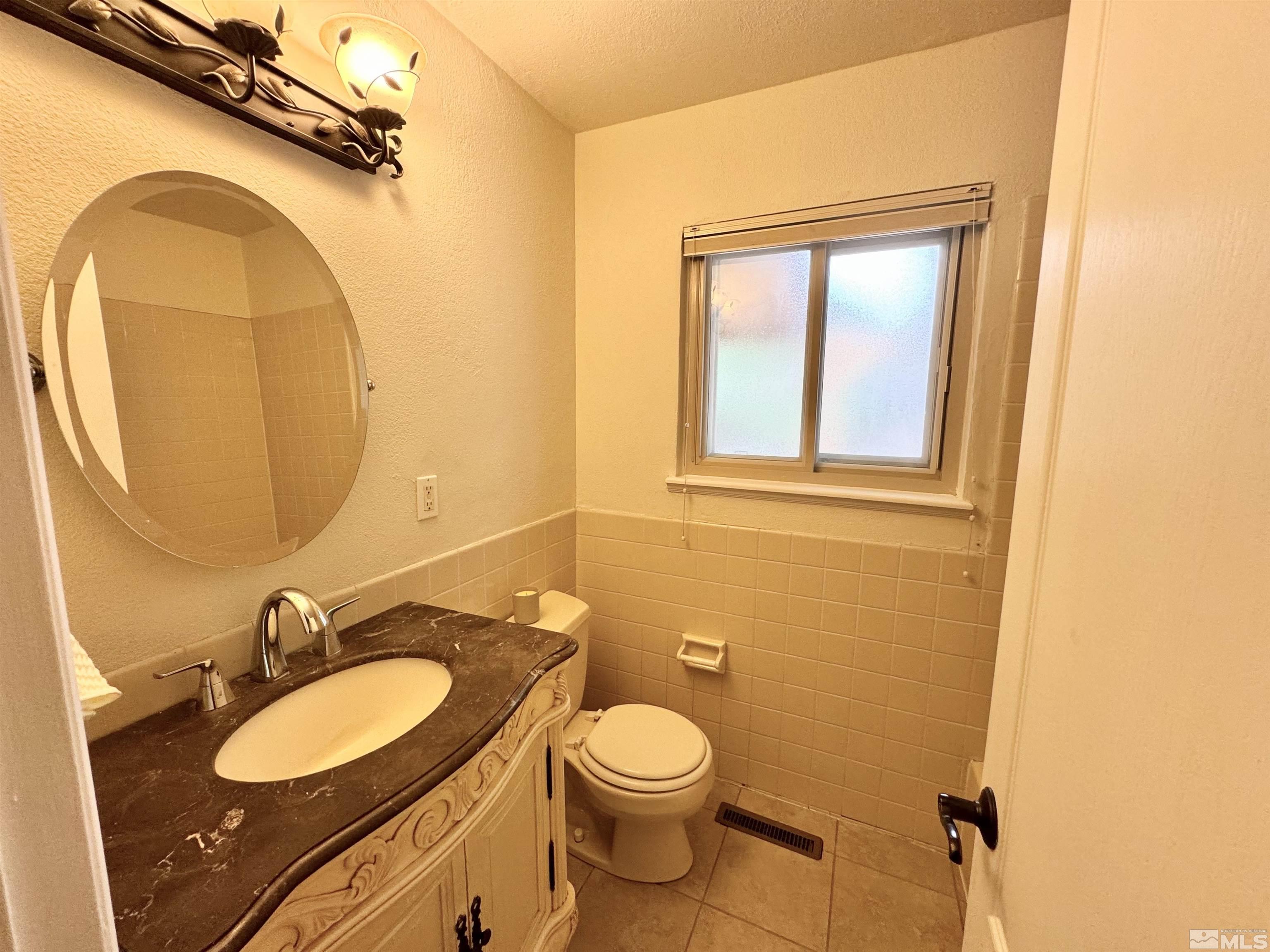 4640 Aster Drive Reno, NV 89502 - Photo 8 of 22 a bathroom with a granite countertop toilet sink and mirror