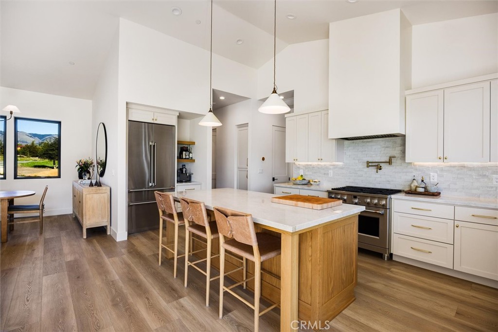 5260 Windmill Way San Luis Obispo, CA 93401 - Photo 7 of 35 a kitchen with stainless steel appliances granite countertop a stove top oven a refrigerator a sink dishwasher and white cabinets with wooden floor