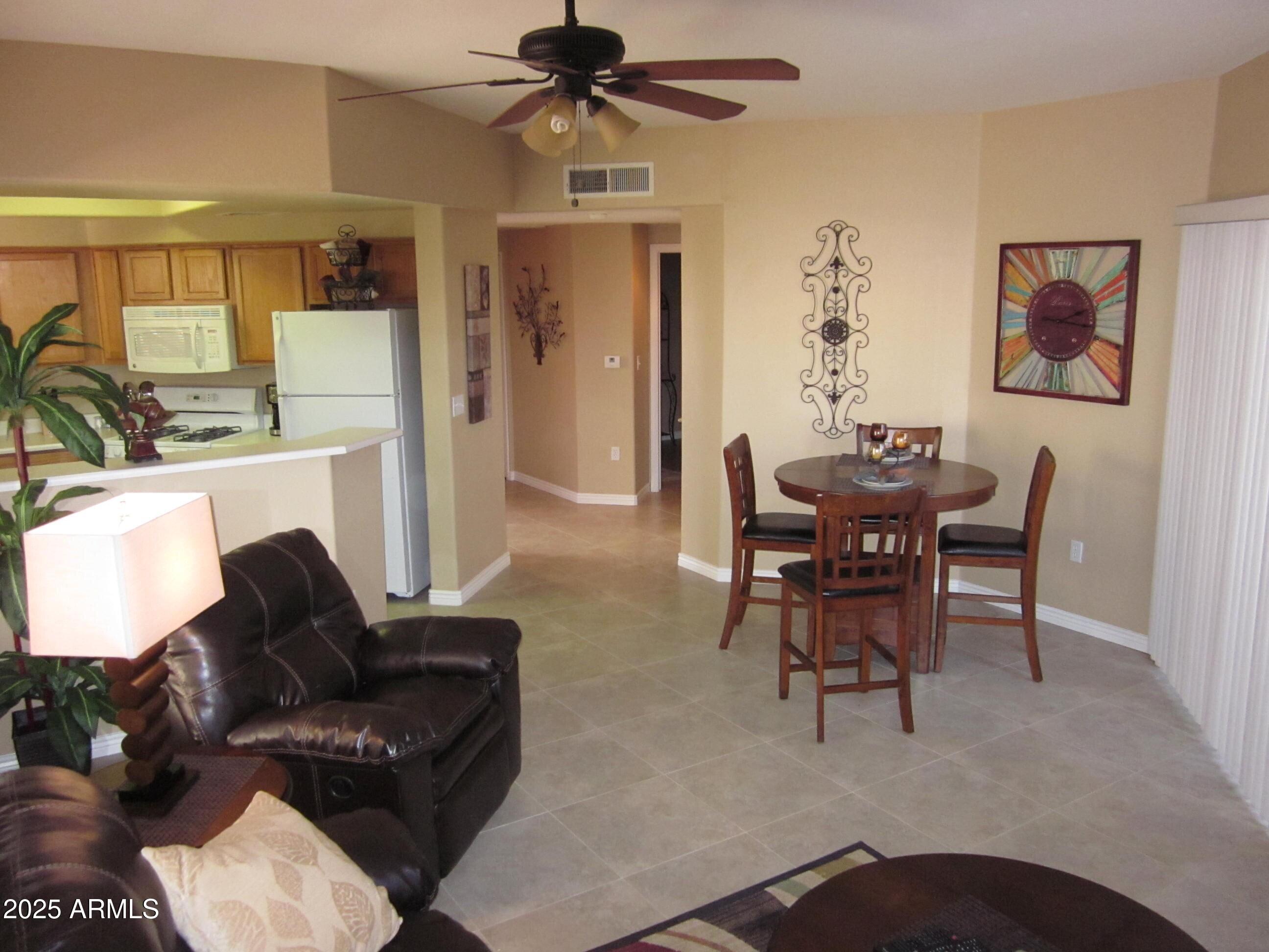 10030 West Indian School Road, Unit 164 Phoenix, AZ 85037 - Photo 11 of 16 a living room with furniture a ceiling fan and a large window
