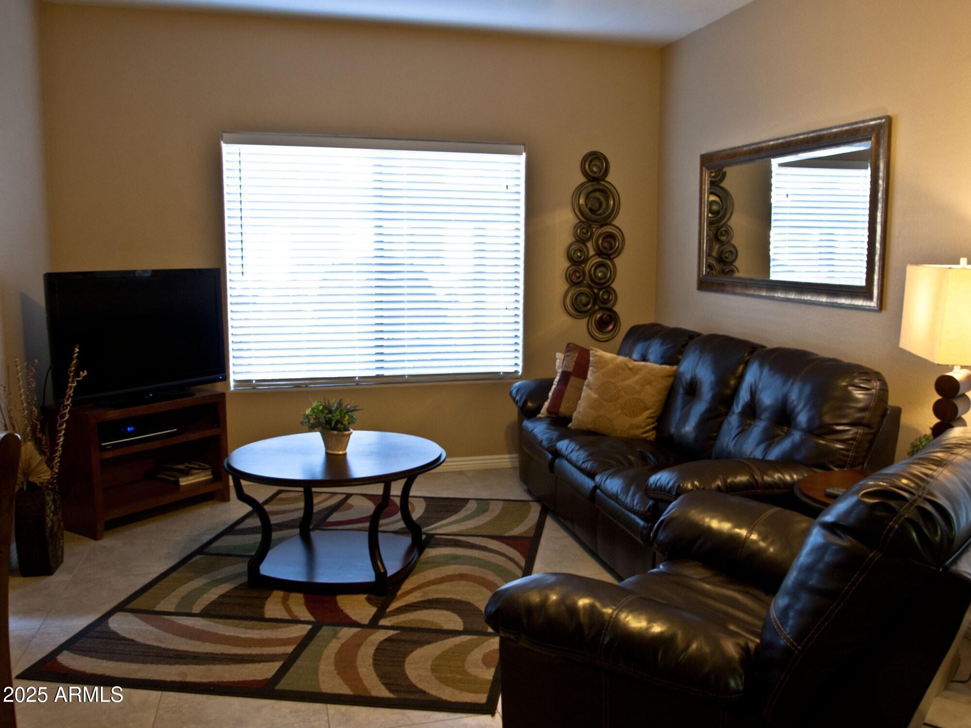 10030 West Indian School Road, Unit 164 Phoenix, AZ 85037 - Photo 12 of 16 a living room with furniture and a flat screen tv