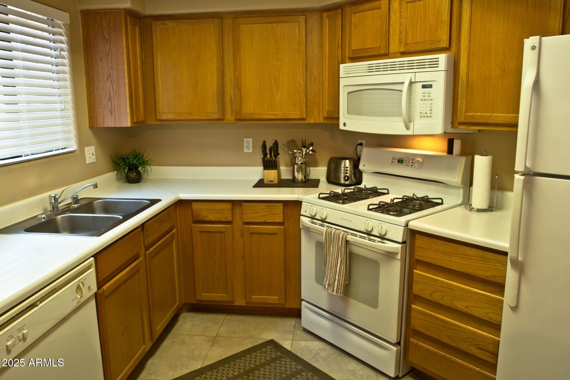 10030 West Indian School Road, Unit 164 Phoenix, AZ 85037 - Photo 13 of 16 a kitchen with a sink stove and cabinets
