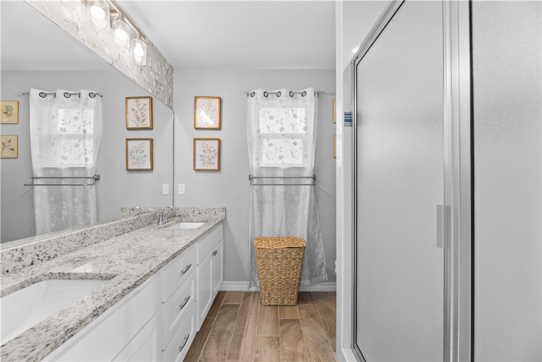 103 Atkinson Drive Orange Grove, TX 78372 - Photo 17 of 30 a bathroom with a granite countertop sink a mirror and a shower