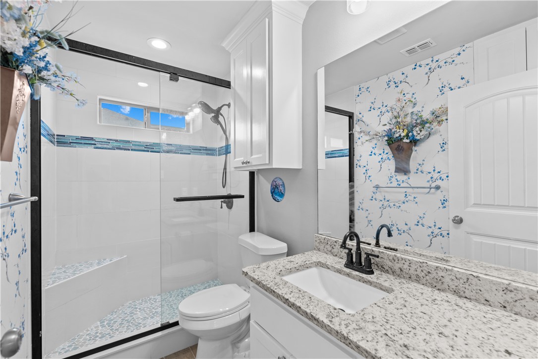 103 Atkinson Drive Orange Grove, TX 78372 - Photo 22 of 30 a bathroom with a granite countertop sink a toilet and a mirror