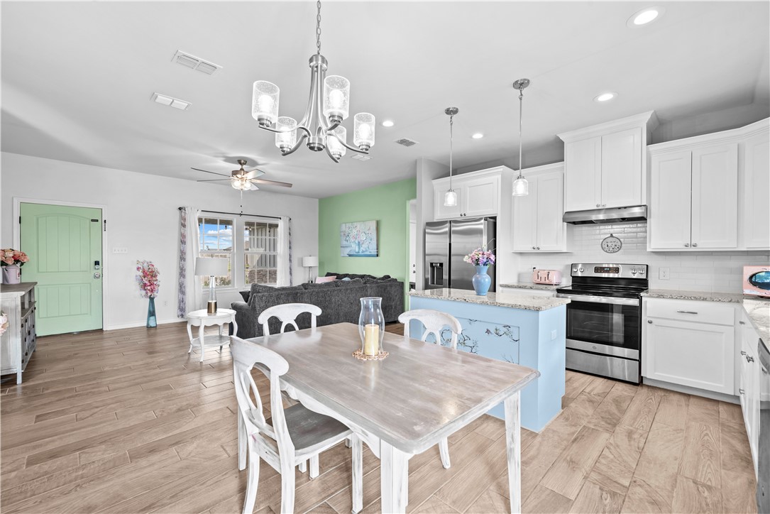 103 Atkinson Drive Orange Grove, TX 78372 - Photo 7 of 30 a kitchen with stainless steel appliances granite countertop a dining table chairs stove and white cabinets