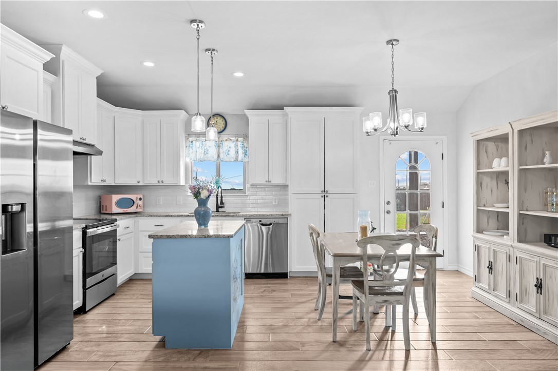 103 Atkinson Drive Orange Grove, TX 78372 - Photo 8 of 30 a kitchen with kitchen island a refrigerator a stove a center island and a wooden floor