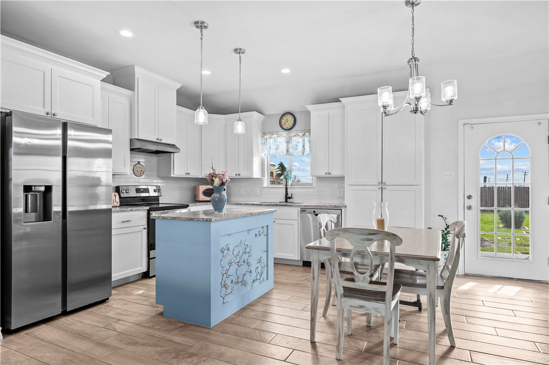 103 Atkinson Drive Orange Grove, TX 78372 - Photo 9 of 30 a kitchen with stainless steel appliances kitchen island granite countertop a table chairs and a refrigerator