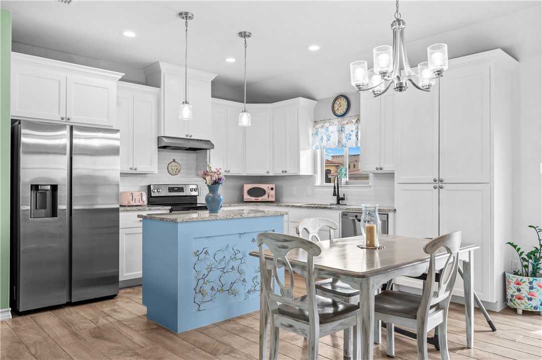 103 Atkinson Drive Orange Grove, TX 78372 - Photo 10 of 30 a kitchen with stainless steel appliances kitchen island granite countertop a refrigerator a stove a kitchen island a dining table and chairs