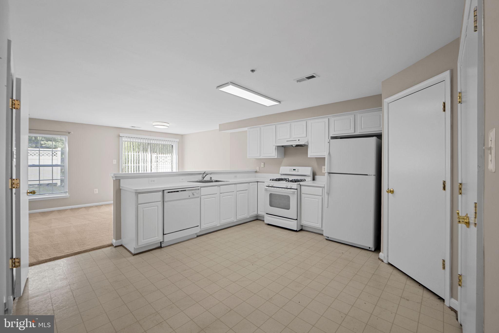 23404 Rainbow Arch Drive, Unit 115 Clarksburg, MD 20871 - Photo 17 of 34 a kitchen with white cabinets and white appliances