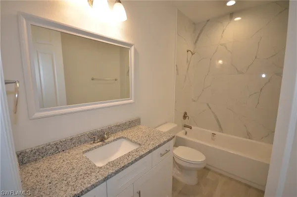 a bathroom with a granite countertop sink toilet and shower
