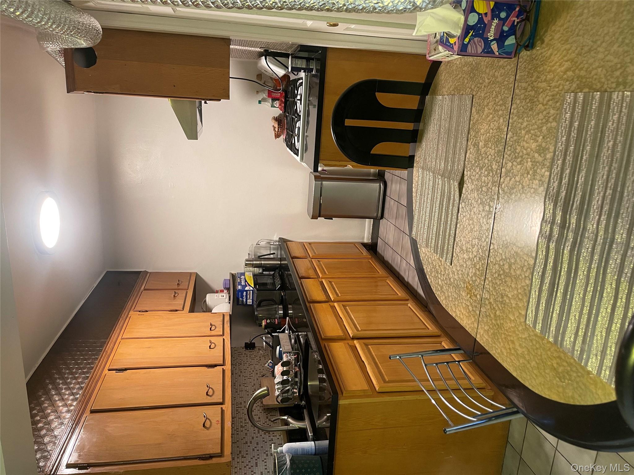 99-35 59th Avenue, Unit 5E Queens, NY 11368 - Photo 6 of 11 Kitchen featuring brown cabinetry, dark stone countertops, light tile patterned floors, extractor fan, and stove