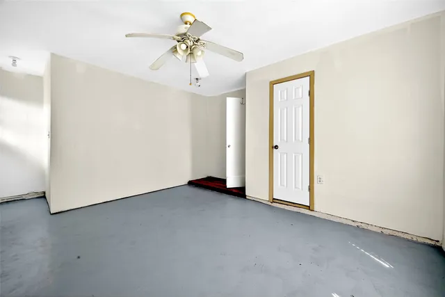 an empty room with a chandelier fan and closet