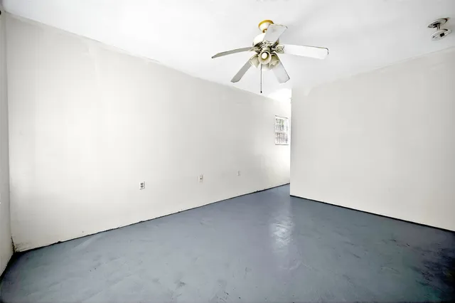 an empty room with a window and a fan