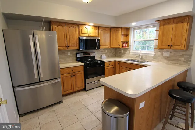 a kitchen with stainless steel appliances granite countertop a refrigerator a sink a stove a microwave a counter space and cabinets