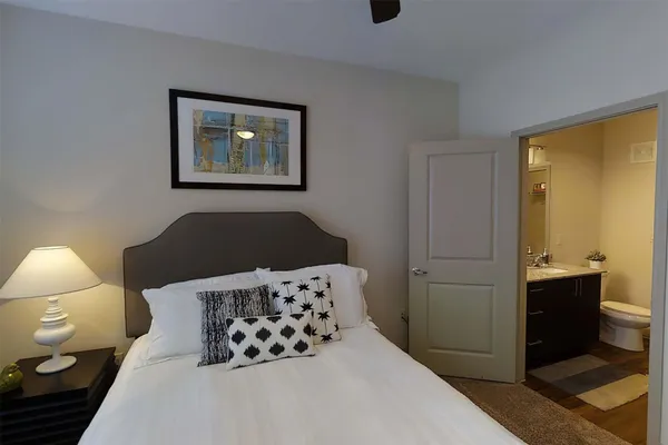 a bedroom with a bed and a lamp on dresser