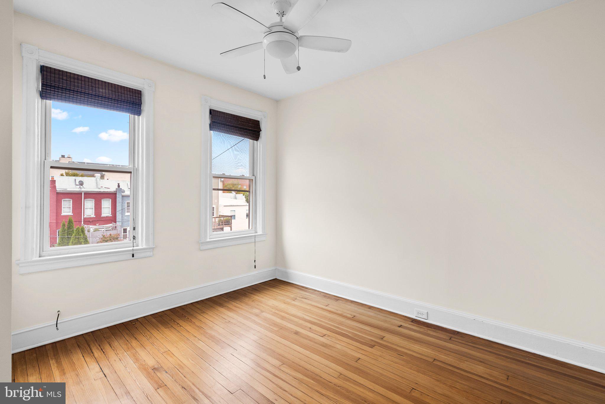 121 U Street Northeast Washington, DC 20002 - Photo 21 of 31 an empty room with wooden floor chandelier fan and windows