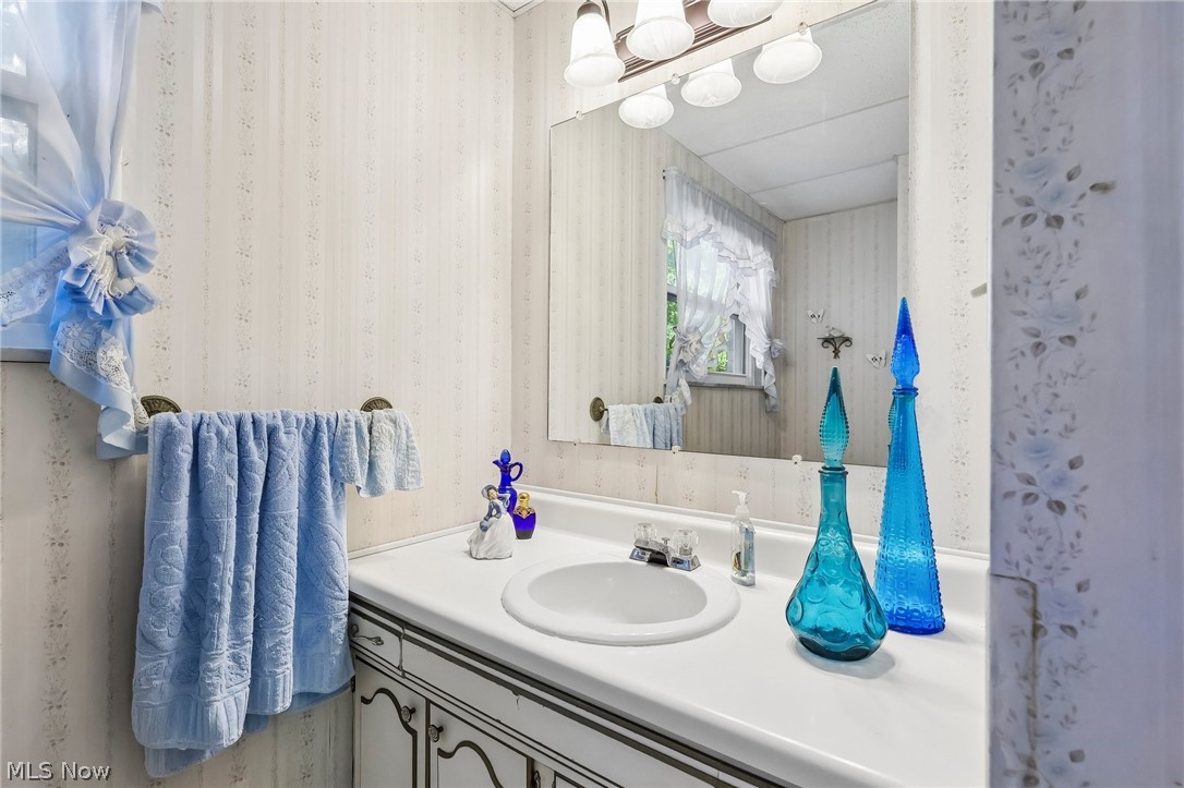 2428 Antioch Road Perry, OH 44081 - Photo 35 of 46 Bathroom vanity featuring an integrated sink, dual-handle faucet, and overhead bar lighting