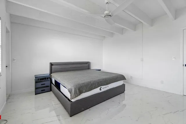 a bed sitting in a spacious bedroom next to a window