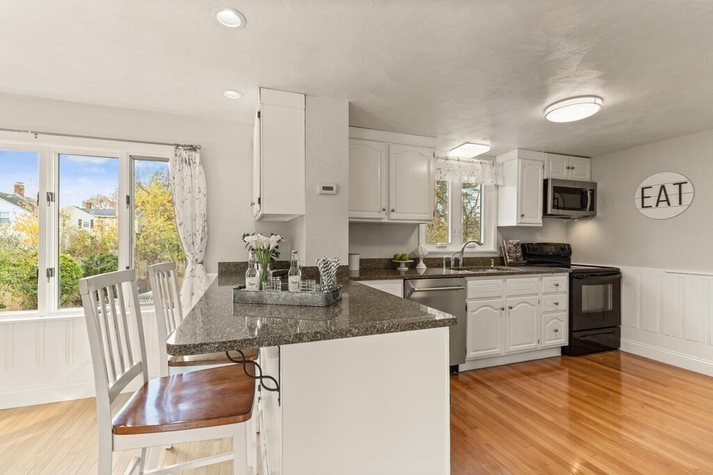 39 Nathaniel Road Winchester, MA 01890 - Photo 13 of 38 a kitchen with stainless steel appliances granite countertop a stove top oven a sink a dining table and chairs with wooden floor