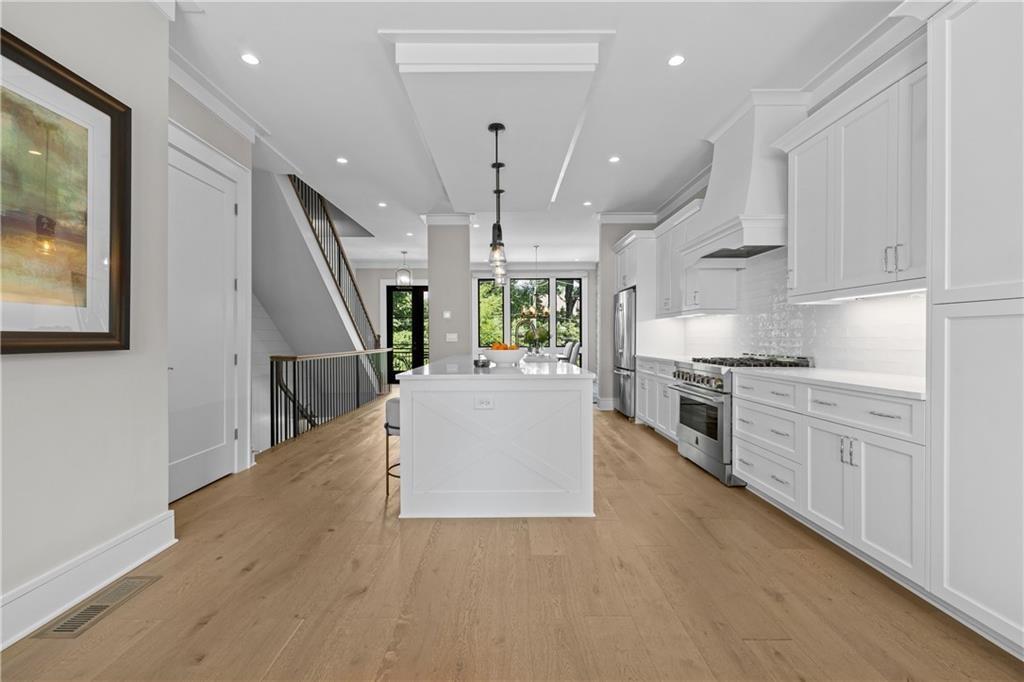 1272 Appleden Way, Unit 19 Atlanta, GA 30319 - Photo 4 of 26 a large white kitchen with stainless steel appliances refrigerator stove and wooden floor