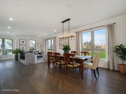 a kitchen with stainless steel appliances granite countertop a stove a refrigerator a kitchen island a dining table and chairs with wooden floor