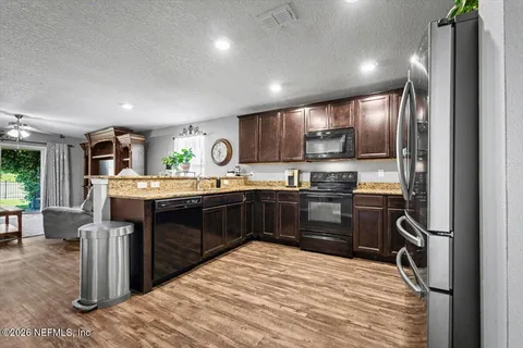 a kitchen with stainless steel appliances kitchen island granite countertop a stove refrigerator and cabinets