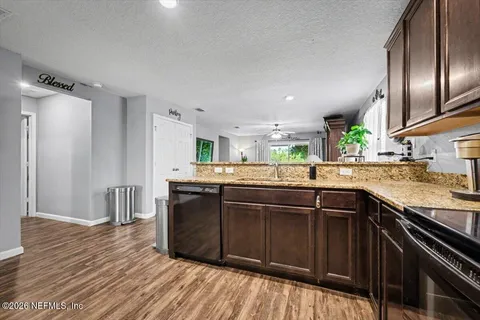 a kitchen with stainless steel appliances granite countertop a sink and wooden floor