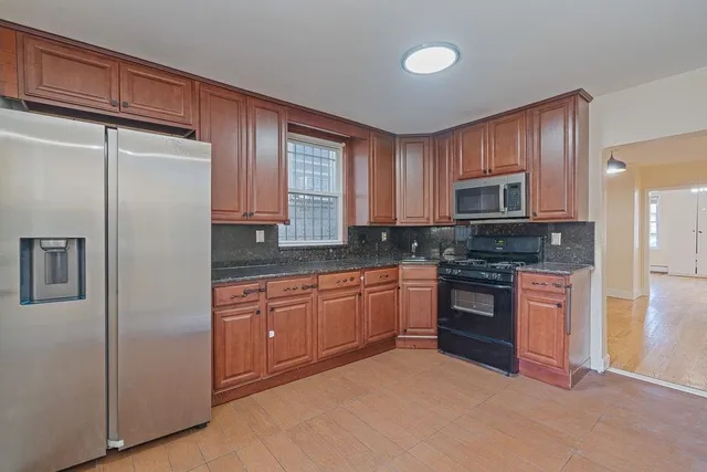 a kitchen with granite countertop stainless steel appliances a refrigerator stove top oven and sink