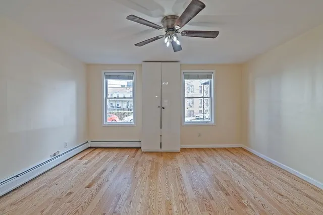 a view of empty room with wooden floor and fan