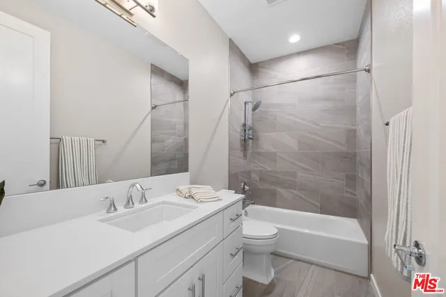 a bathroom with a bathtub shower sink vanity mirror and toilet