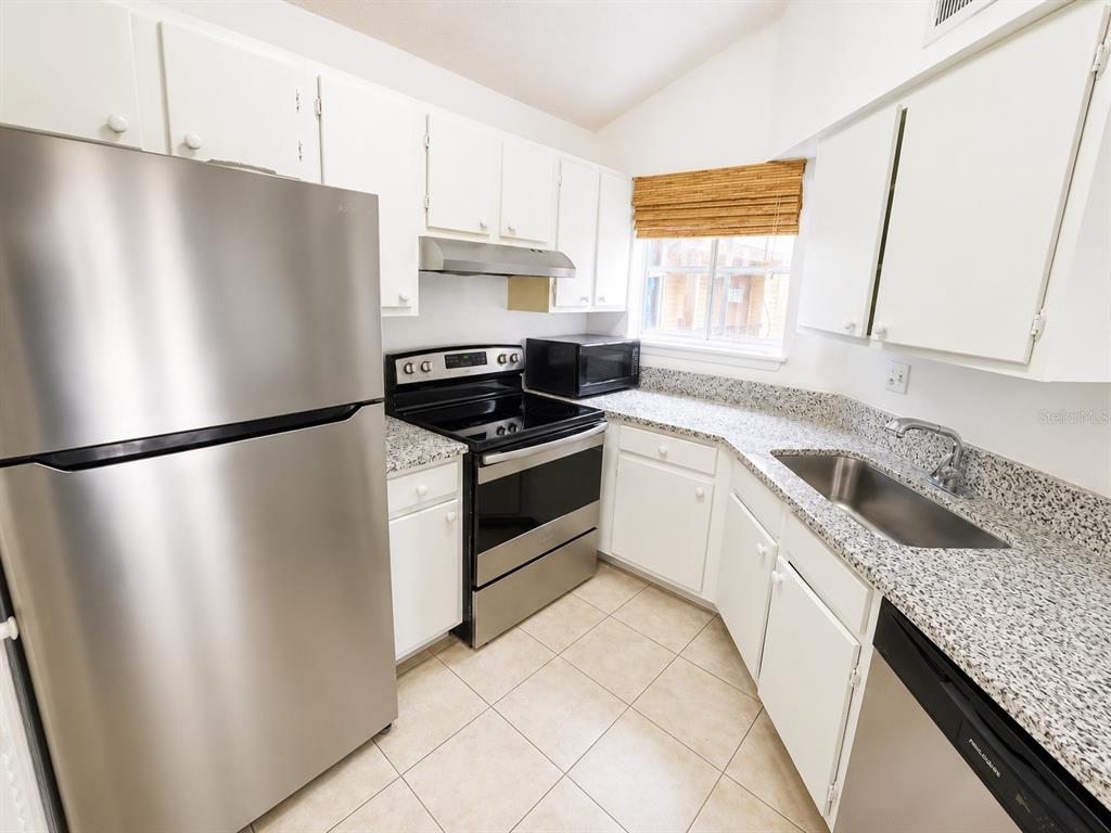 1908 Lake Atriums Circle, Unit 9 Orlando, FL 32839 - Photo 3 of 11 a kitchen with granite countertop a refrigerator and a sink
