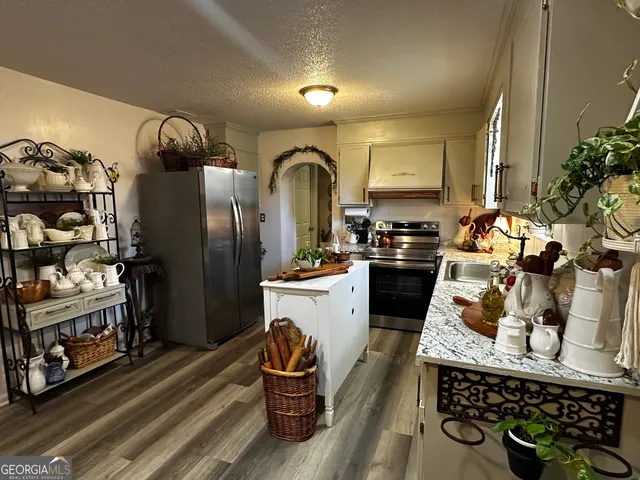 a kitchen with stainless steel appliances granite countertop a refrigerator a stove and a sink