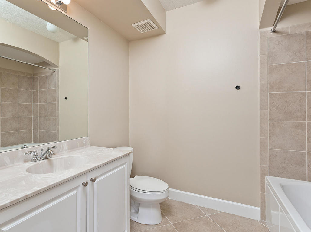 4 Renaissance Way, Unit 303 Boynton Beach, FL 33426 - Photo 23 of 26 a bathroom with a granite countertop sink a toilet and a mirror