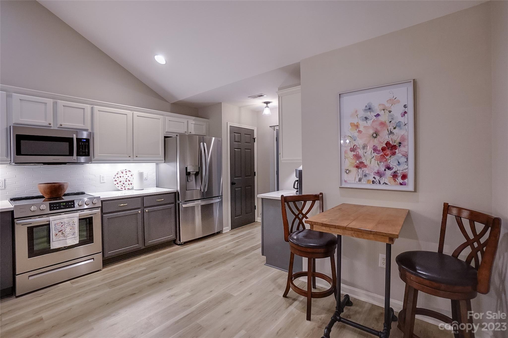 815 Ledgestone Court Tega Cay, SC 29708 - Photo 17 of 39 a kitchen with stainless steel appliances granite countertop a stove top oven a sink dishwasher a dining table and chairs with wooden floor