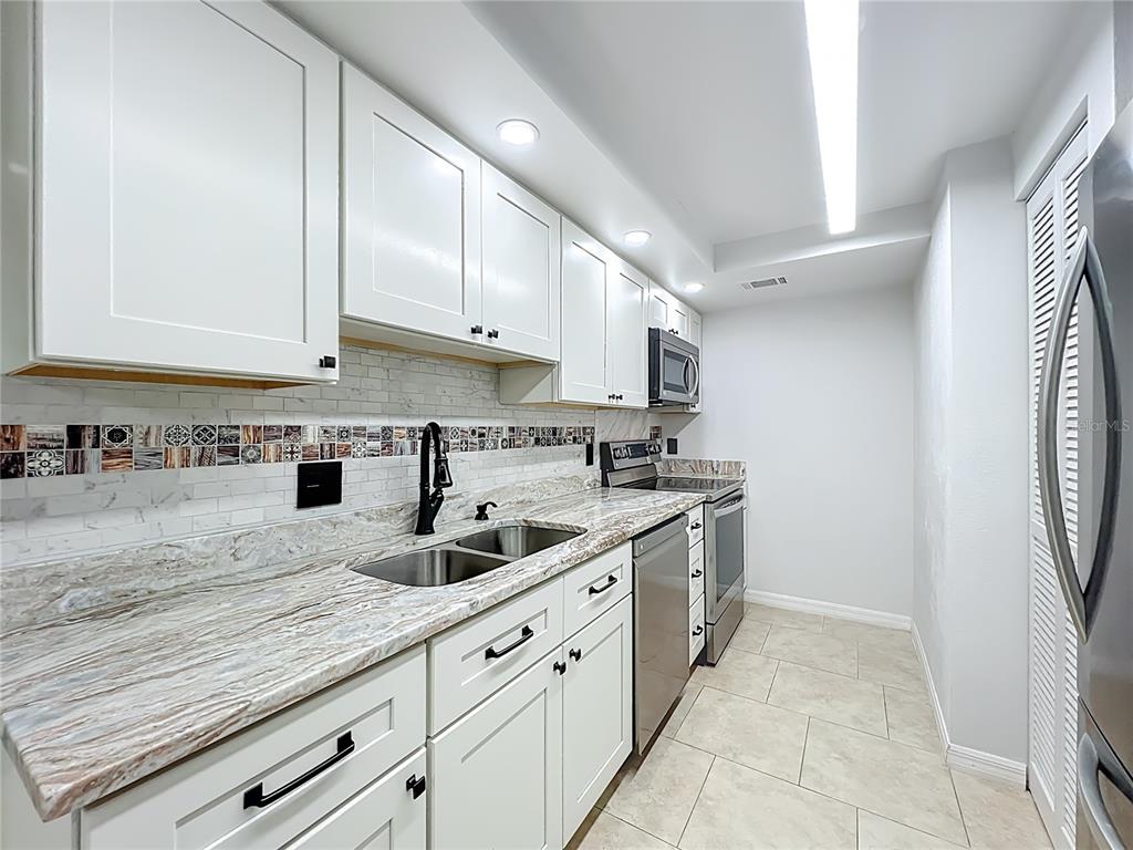 5249 Vineland Road Orlando, FL 32811 - Photo 15 of 42 a kitchen with stainless steel appliances granite countertop a sink and cabinets
