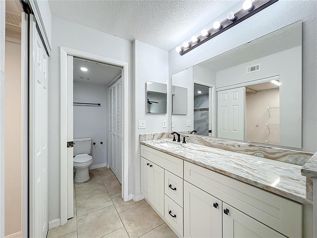 5249 Vineland Road Orlando, FL 32811 - Photo 21 of 42 a spacious bathroom with a granite countertop sink a toilet and a mirror
