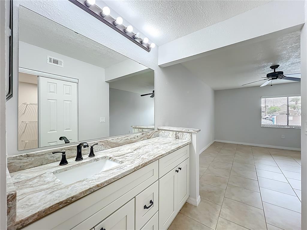 5249 Vineland Road Orlando, FL 32811 - Photo 23 of 42 a bathroom with a granite countertop sink and a mirror