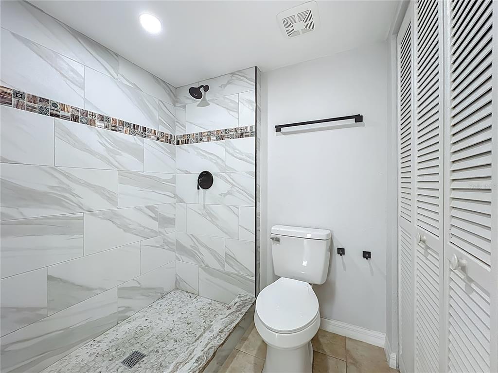5249 Vineland Road Orlando, FL 32811 - Photo 24 of 42 a bathroom with a granite countertop toilet a sink and shower