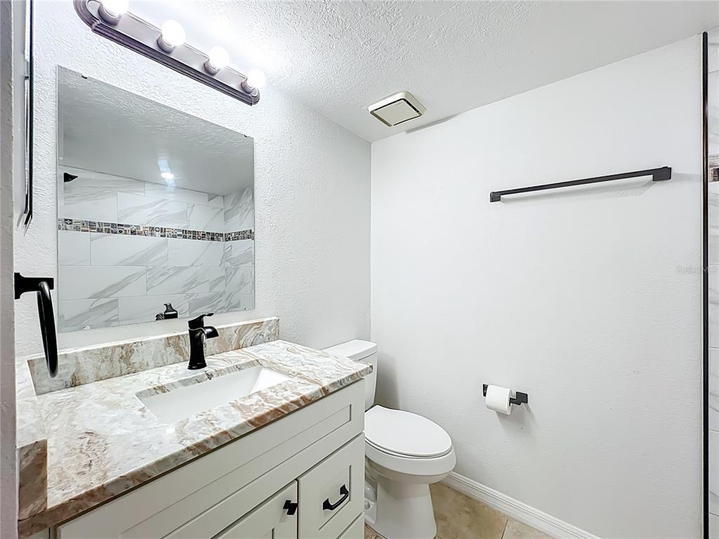5249 Vineland Road Orlando, FL 32811 - Photo 31 of 42 a bathroom with a granite countertop sink toilet and a mirror