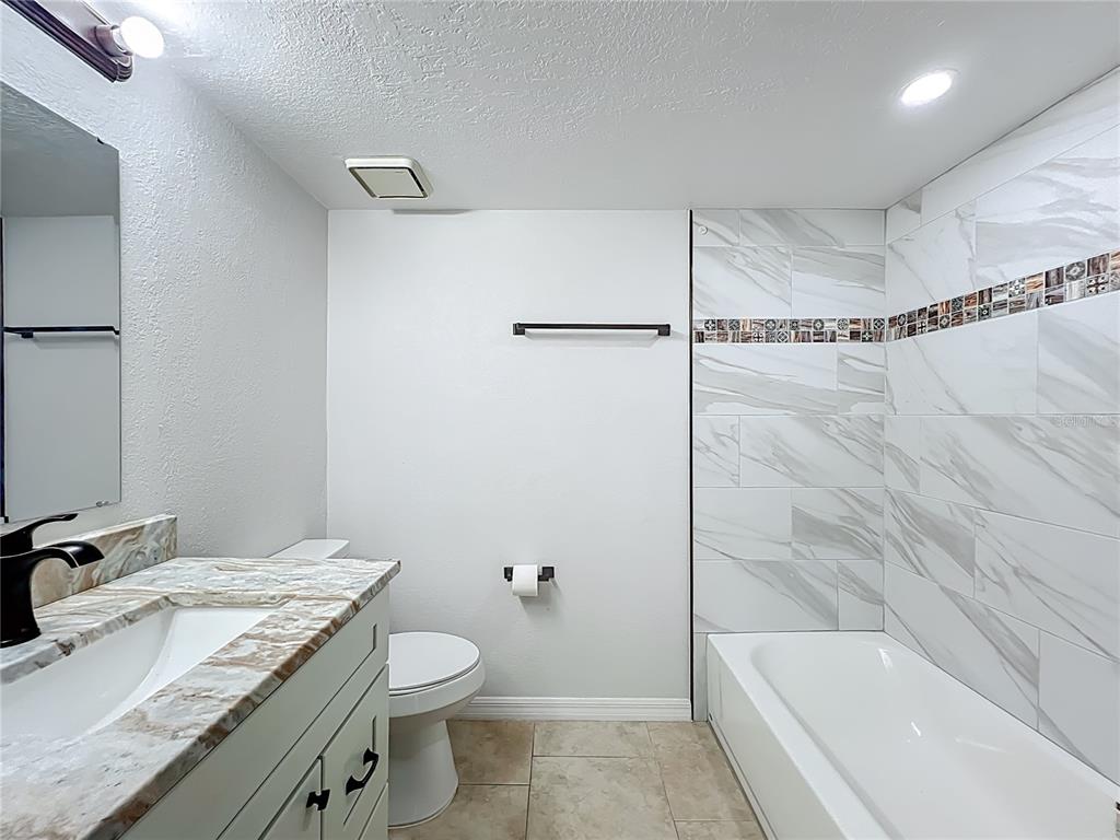 5249 Vineland Road Orlando, FL 32811 - Photo 32 of 42 a bathroom with a granite countertop sink toilet and shower