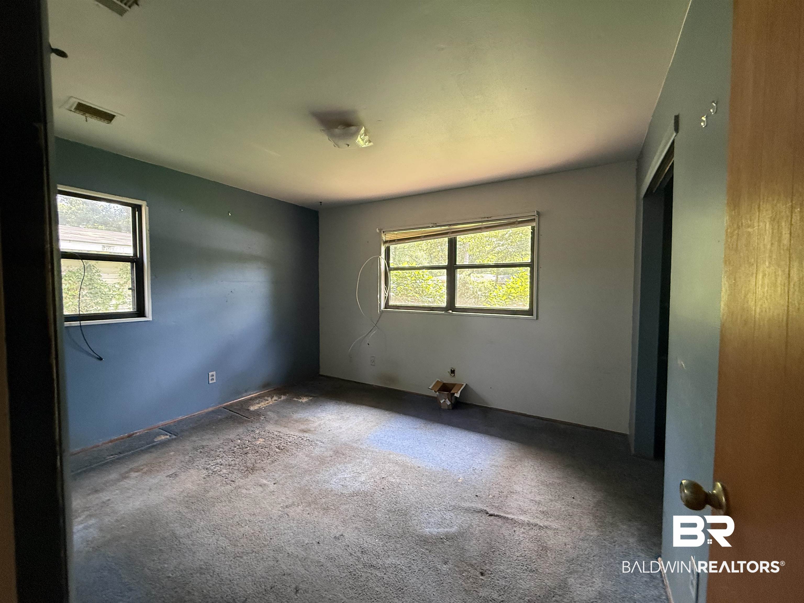 711 Wilshire Road Mobile, AL 36609 - Photo 8 of 11 Spacious room featuring multiple windows, a ceiling-mounted light fixture, and a built-in closet with a bi-fold door