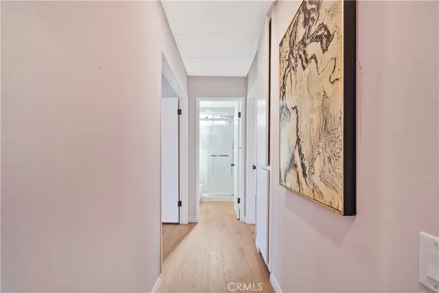 a view of a hallway with wooden floor and a bathroom