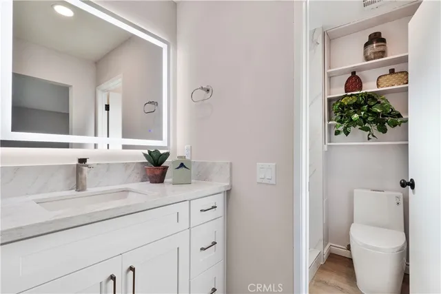 a bathroom with a granite countertop sink vanity mirror and toilet