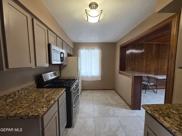 a kitchen with granite countertop a sink a stove and cabinets