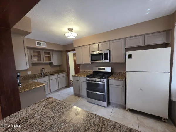 a kitchen with stainless steel appliances granite countertop a refrigerator sink stove microwave and cabinets