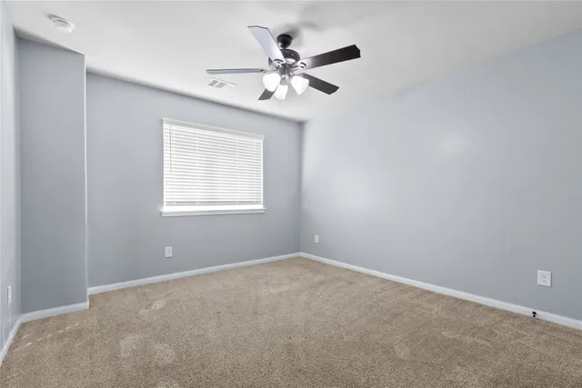 an empty room with a window and a fan
