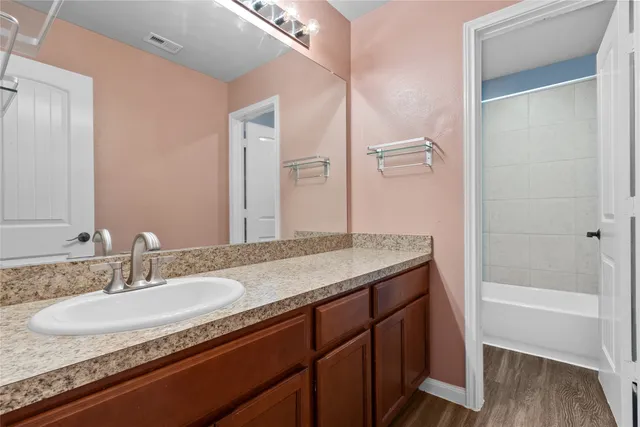 a bathroom with a granite countertop sink a mirror and a bathtub