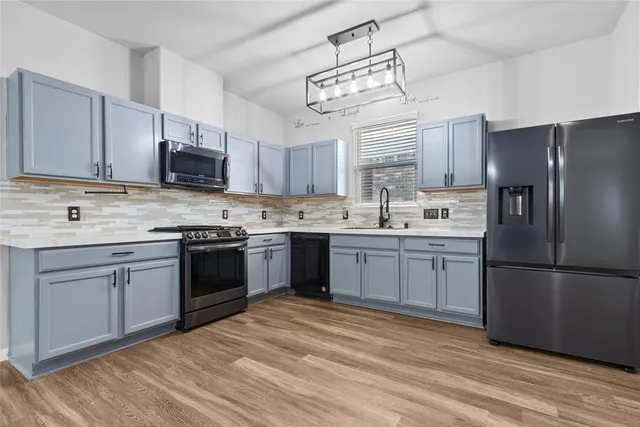 a kitchen with stainless steel appliances granite countertop a refrigerator a sink dishwasher a stove top oven a kitchen island and cabinets with wooden floor